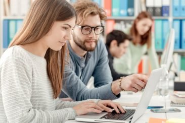 Jóvenes señalando pantalla de computadora portatil